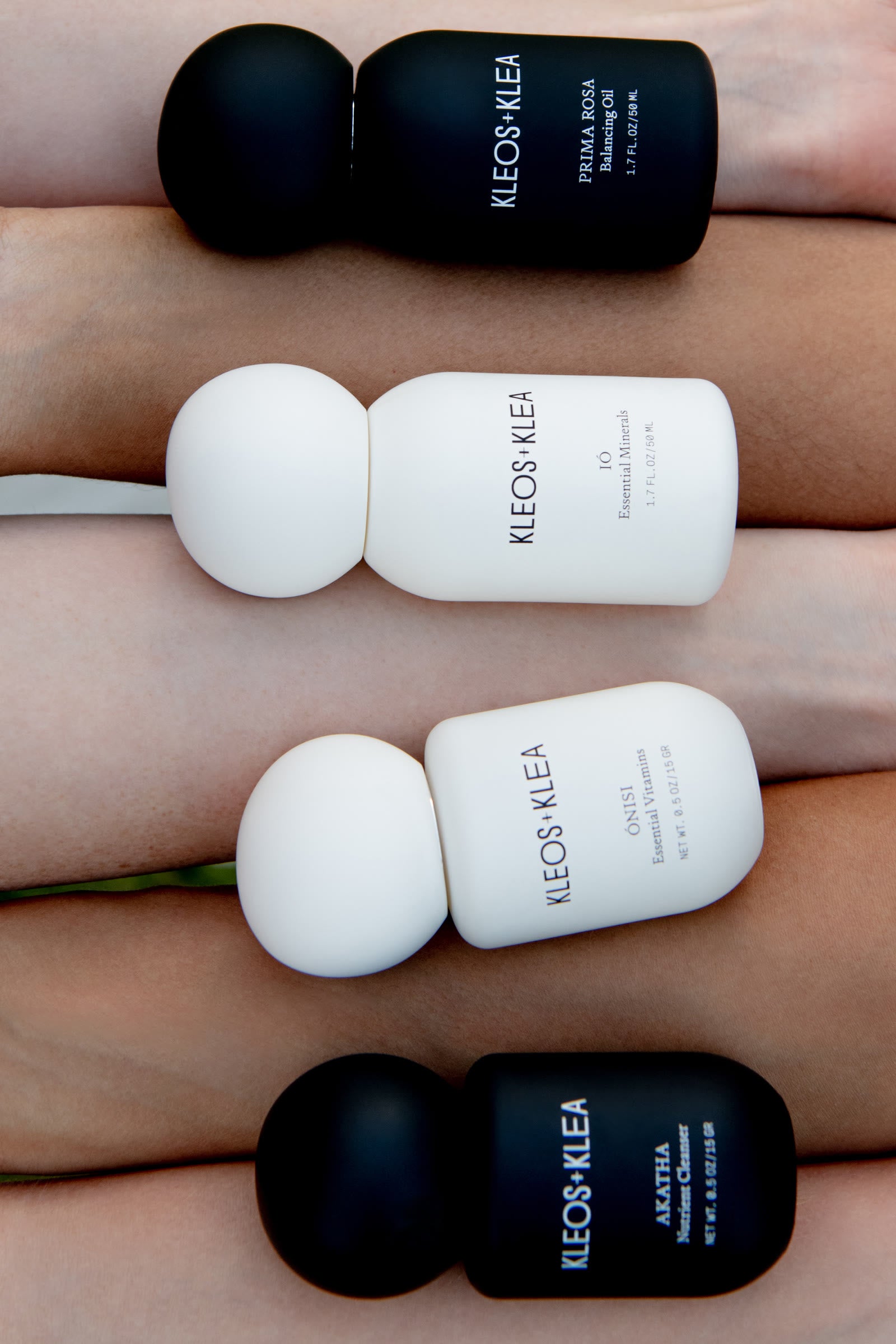 The four KLEOS+KLEA bottles resting across a row of forearms